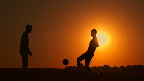 Zwei-Jungen-Spielen-Bei-Sonnenuntergang-Fußball.-Silhouette-Von-Kindern,-Die-Bei-Sonnenuntergang-Mit-Einem-Ball-Spielen.-Das-Konzept-Einer-Glücklichen-Familie.